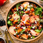 fall harvest salad in a pretty wooden bowl with salad servers on the side.