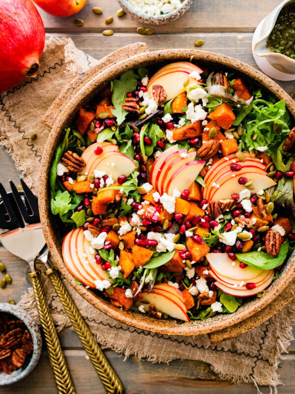fall harvest salad in a pretty wooden bowl with salad servers on the side.