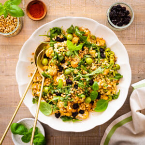 Two spoons in a dish of warm fregola salad with roasted cauliflower.