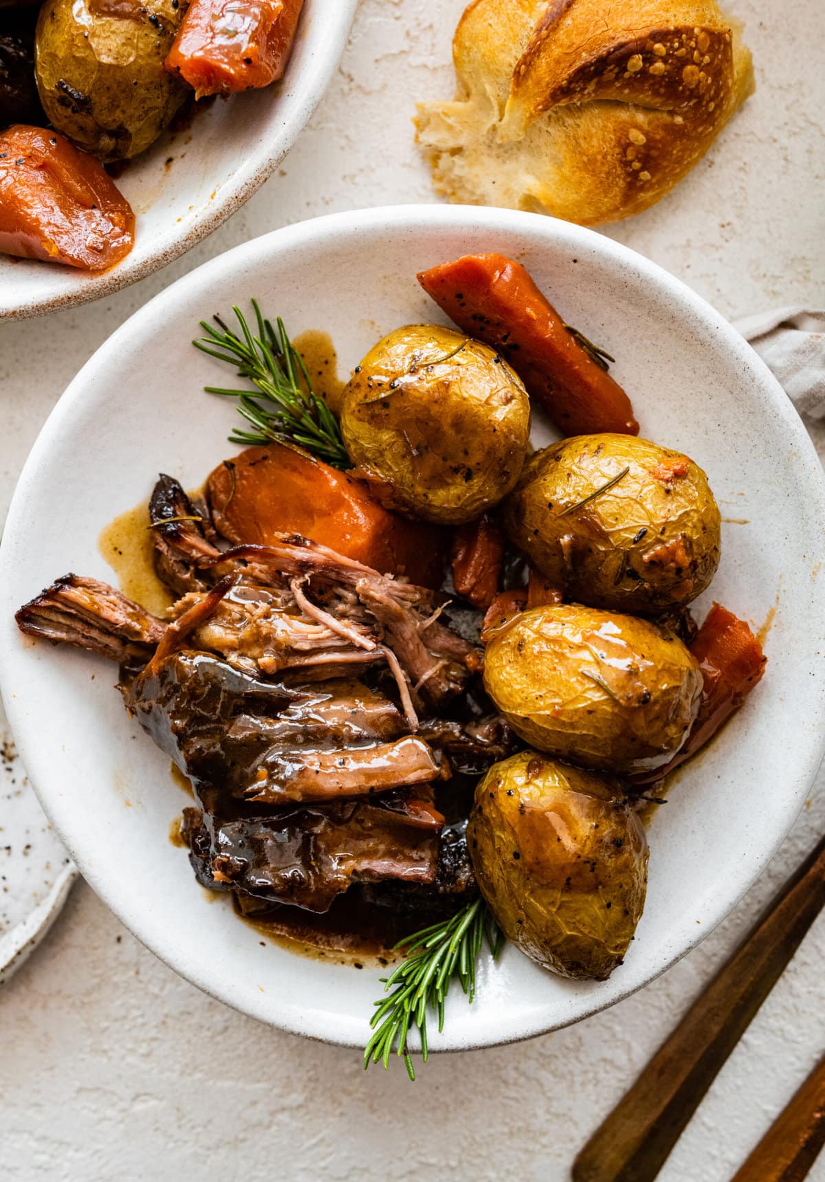 a single plate of fork tender pot roast with vegetables and gravy.