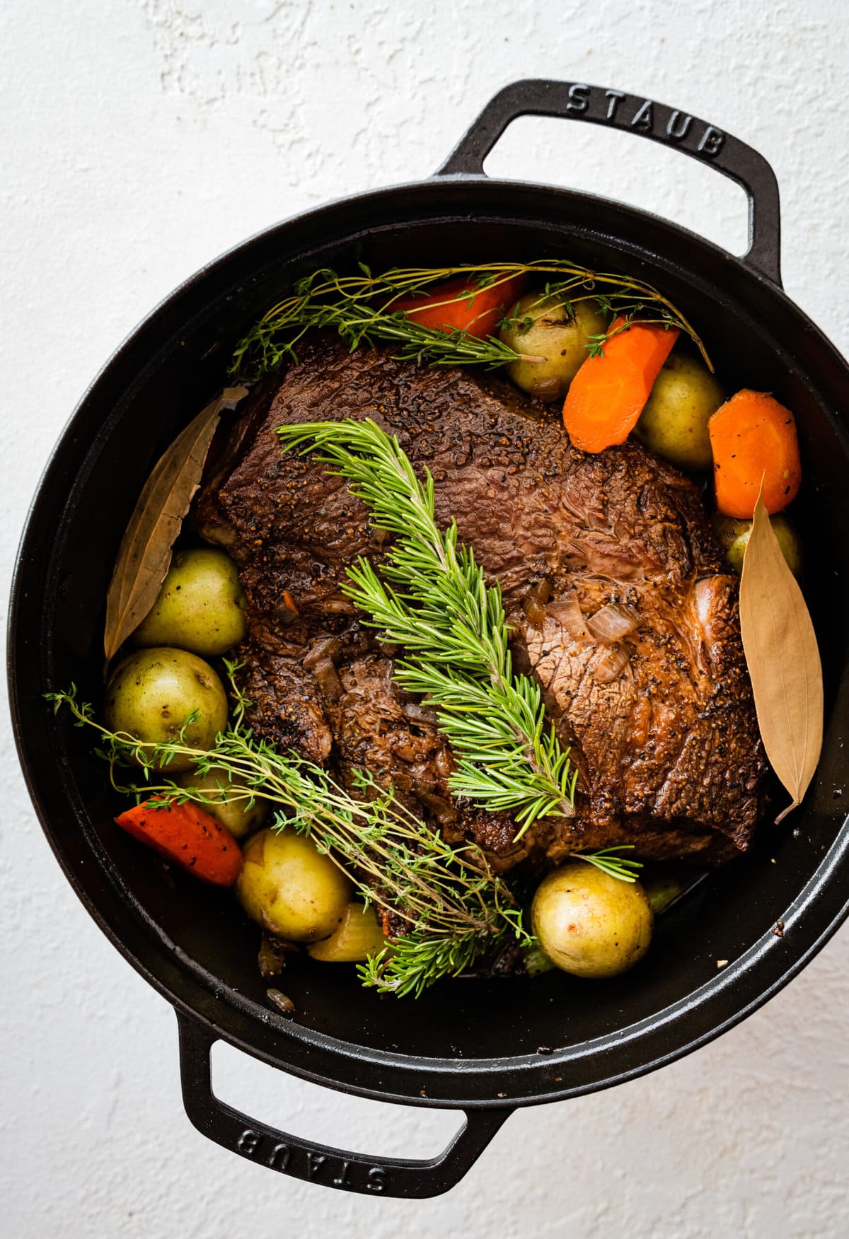 How to make the best perfect pot roast: add meat and herbs to the pot with vegetables.