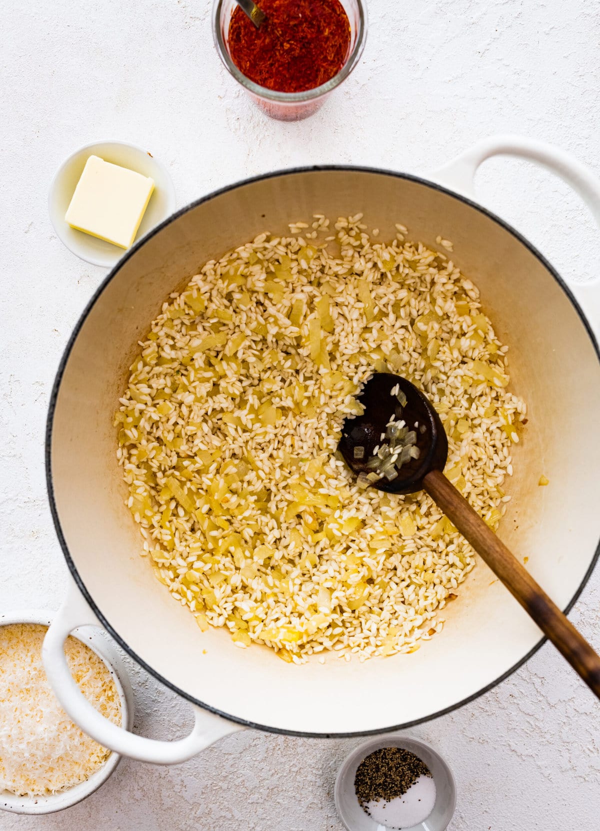 How to make risotto alla milanese step-by-step: sautéing the rice in the pot with wooden spoon.