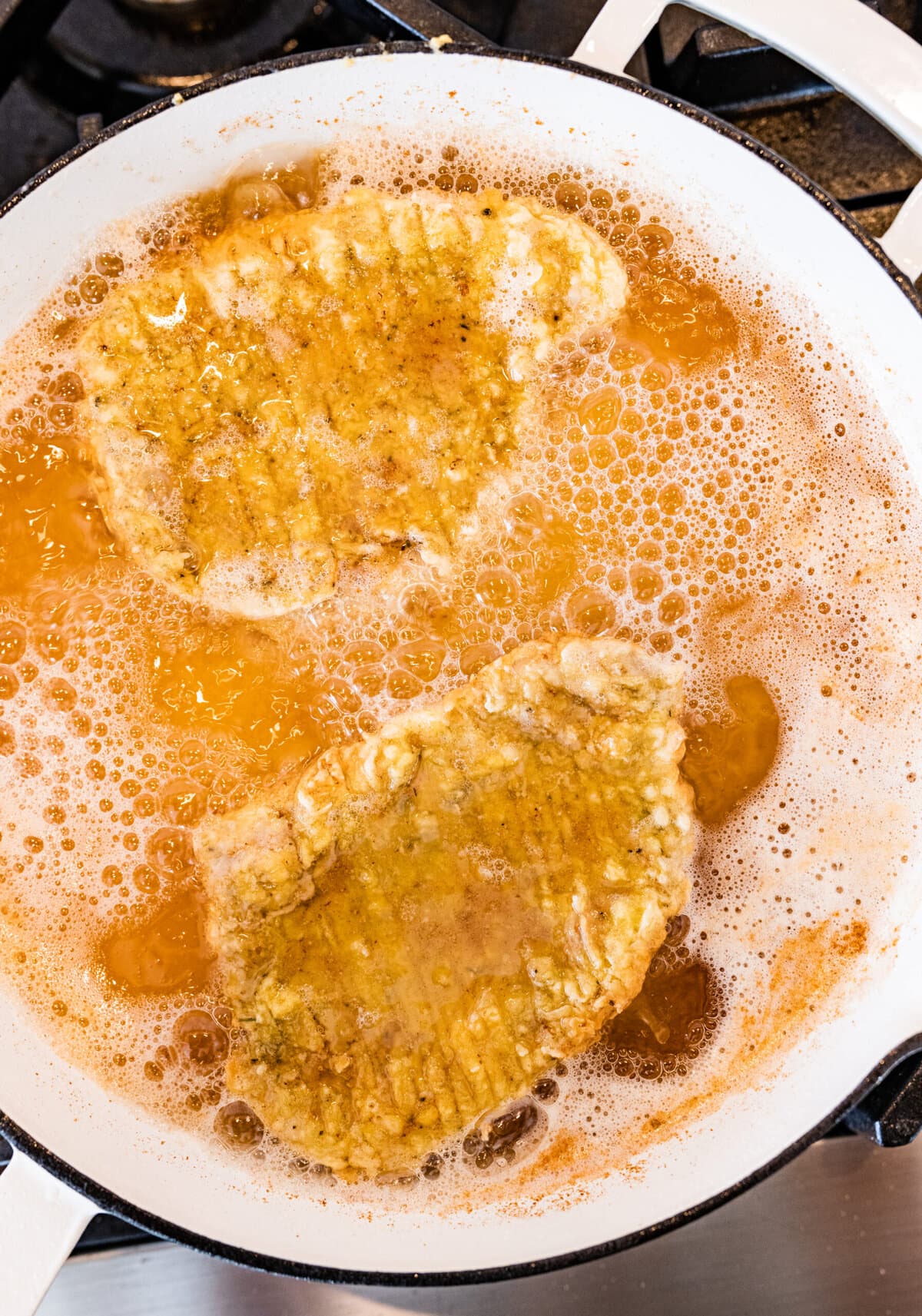 How to make crispy fried pork chops (step-by-step instructions)- frying pork chops in oil on both sides.