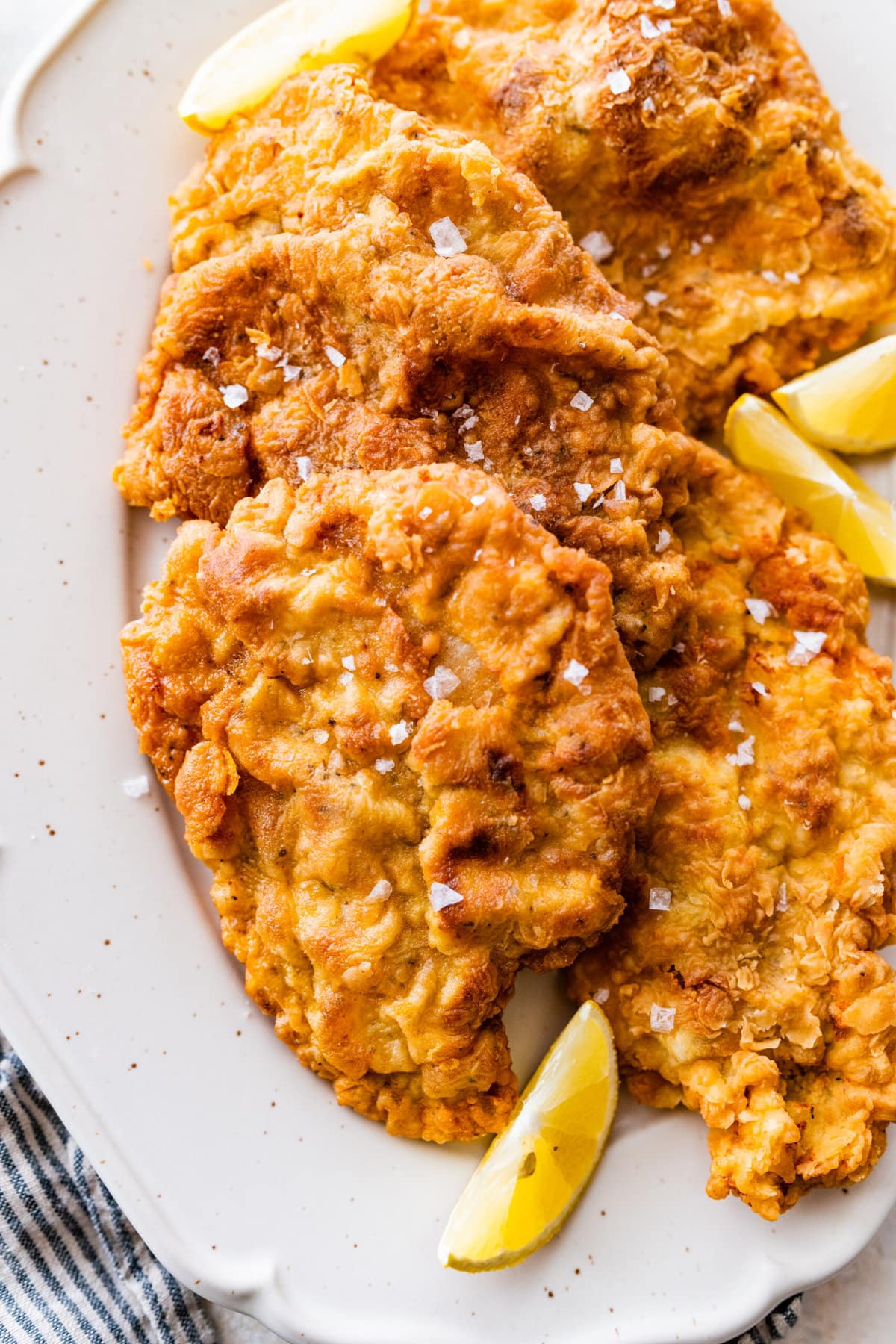 How to make crispy fried pork chops (step-by-step instructions)- finished pork chops on a plate with lemon and salt.