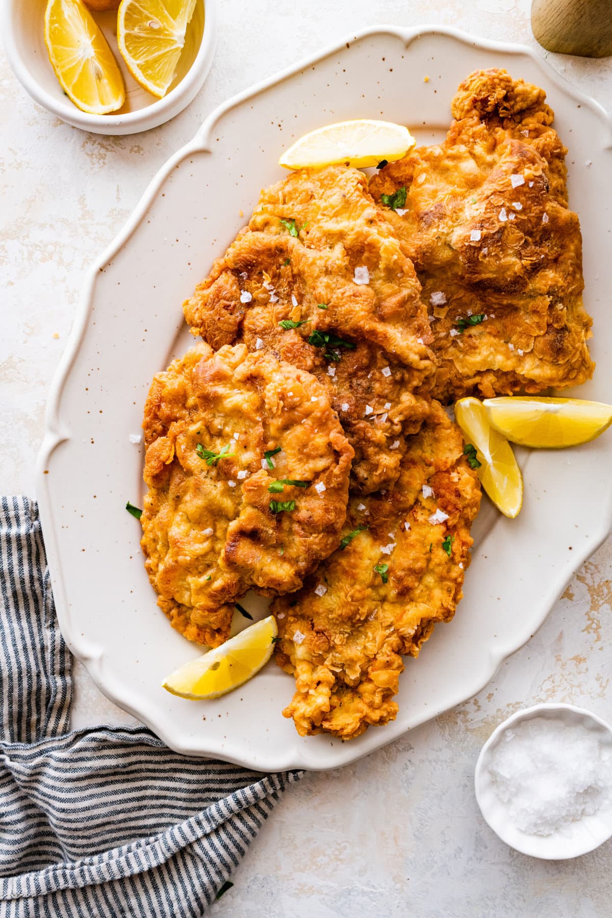 crispy fried pork chops on a plate with lemon wedges.