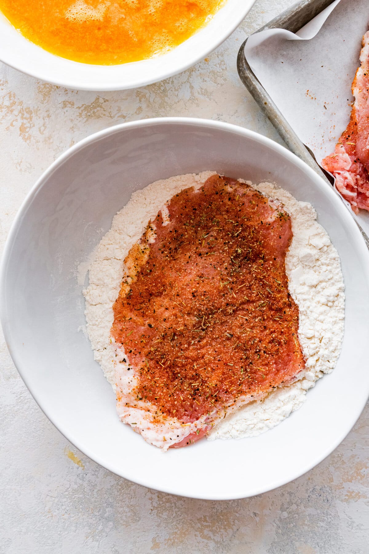 How to make crispy fried pork chops (step-by-step instructions)- coating the pork in flour.
