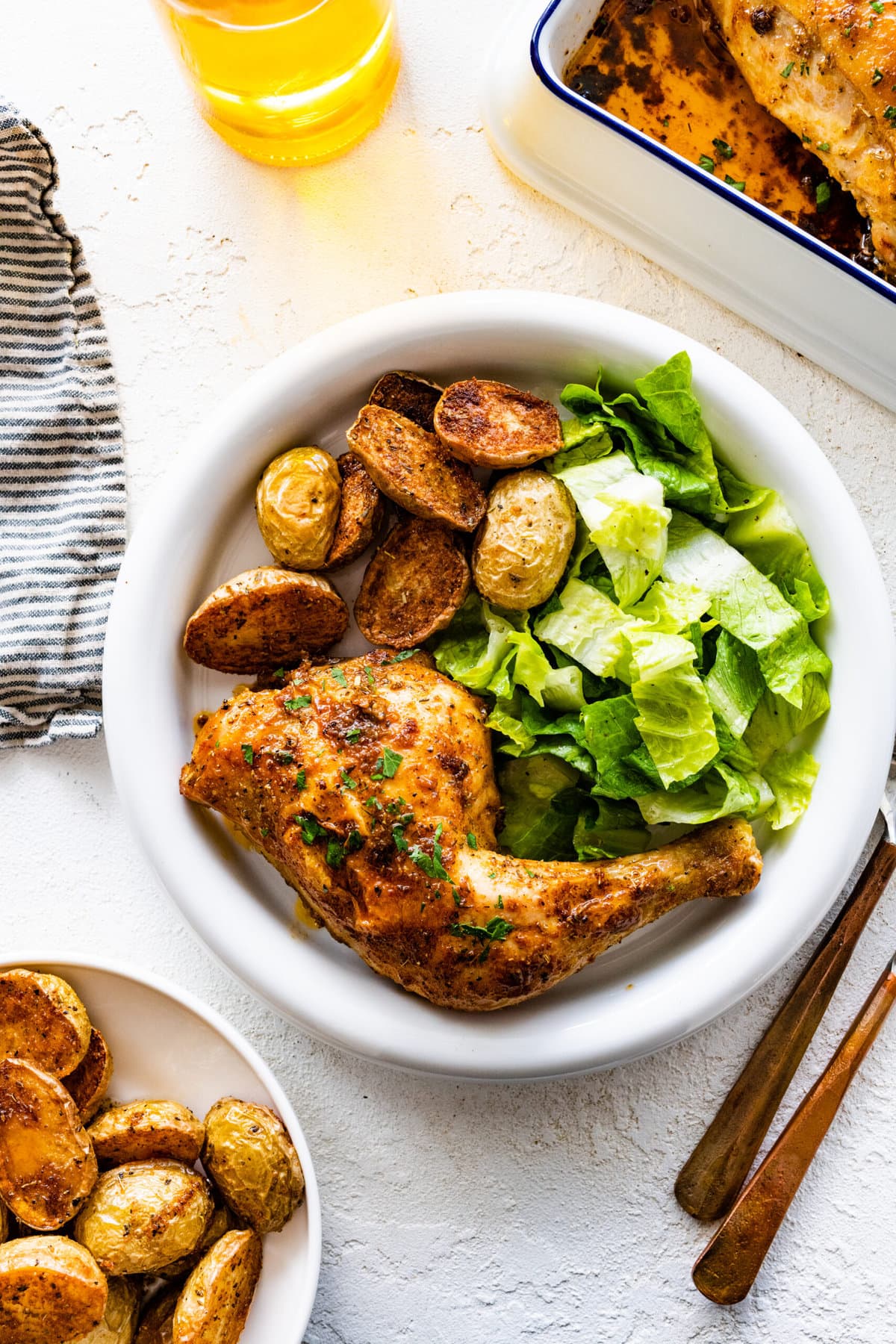 platted baked chicken with potatoes and salad.