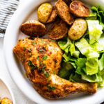 platted baked chicken with potatoes and salad.