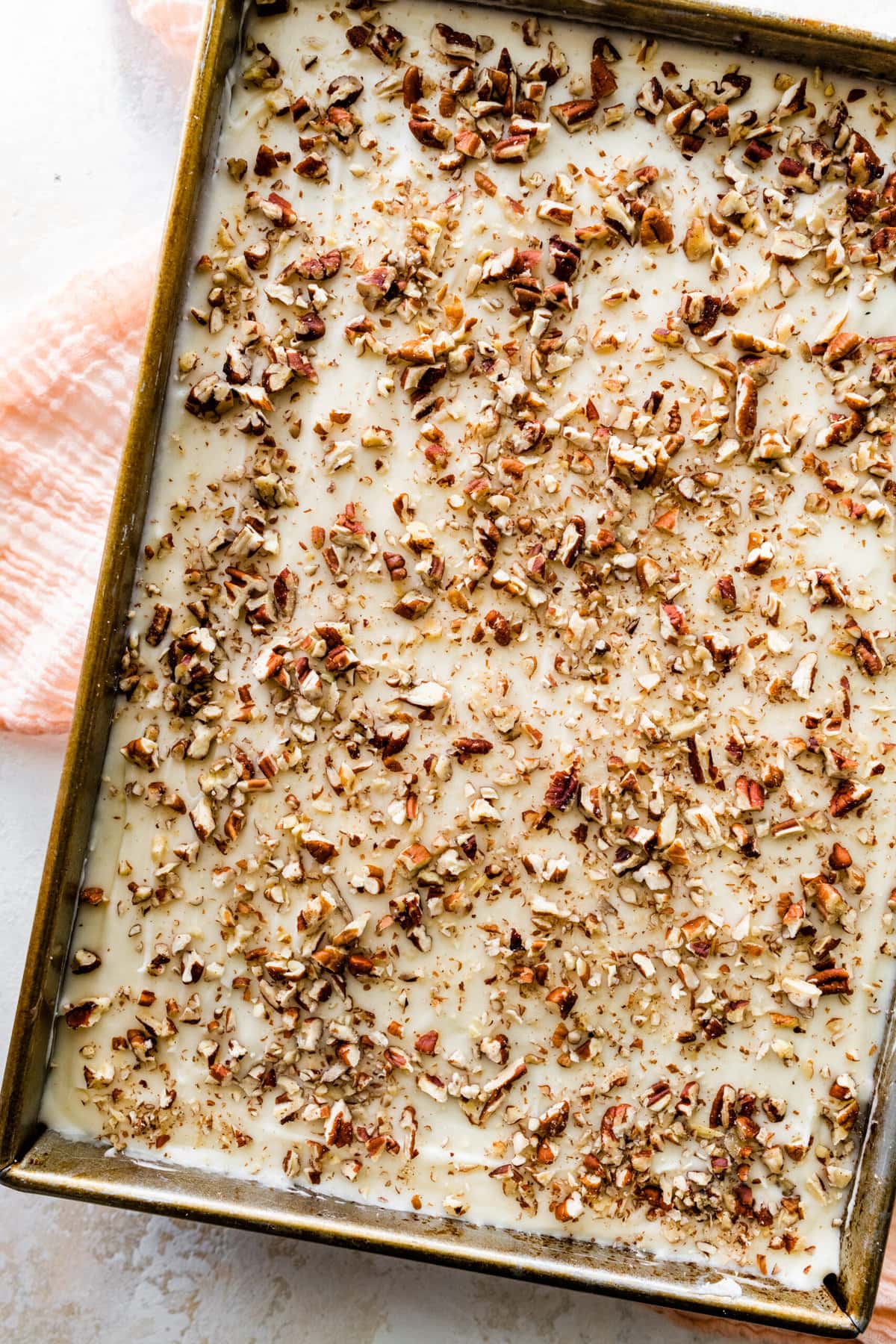 frosted cake in the pan with nuts.