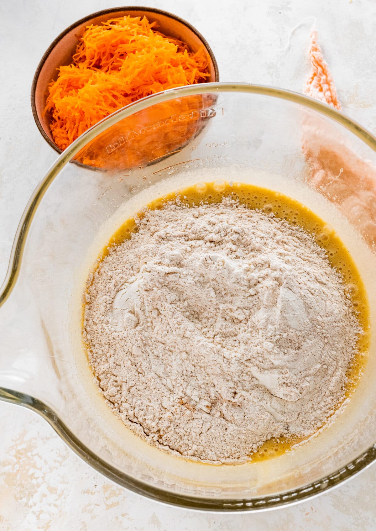 How to make easy carrot cake step-by-step photos: adding the dry ingredients to the bowl with the wet ingredients.