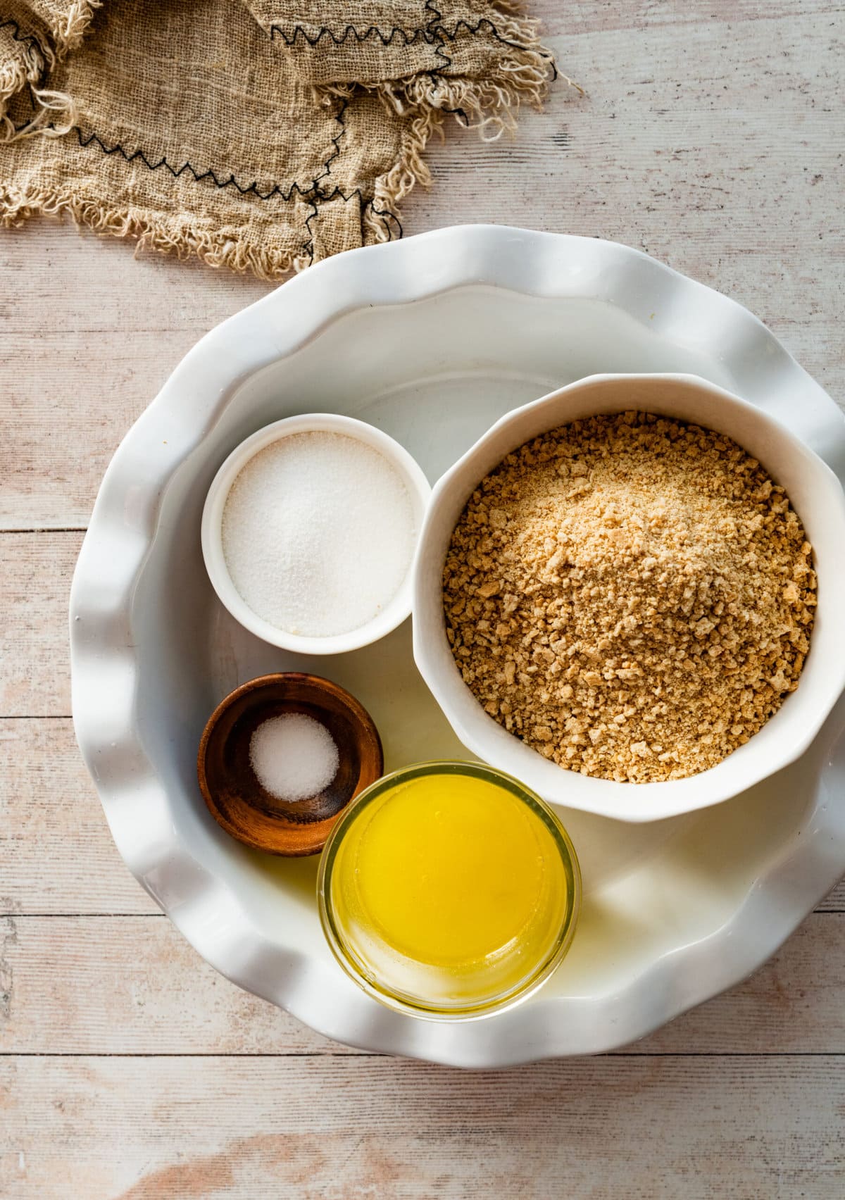 Graham cracker crust ingredients in bowls in a pie plate.