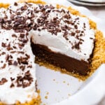 topping the pie with chocolate shaving and ready to serve. Slice of pie taken out to show inside layer of pie.