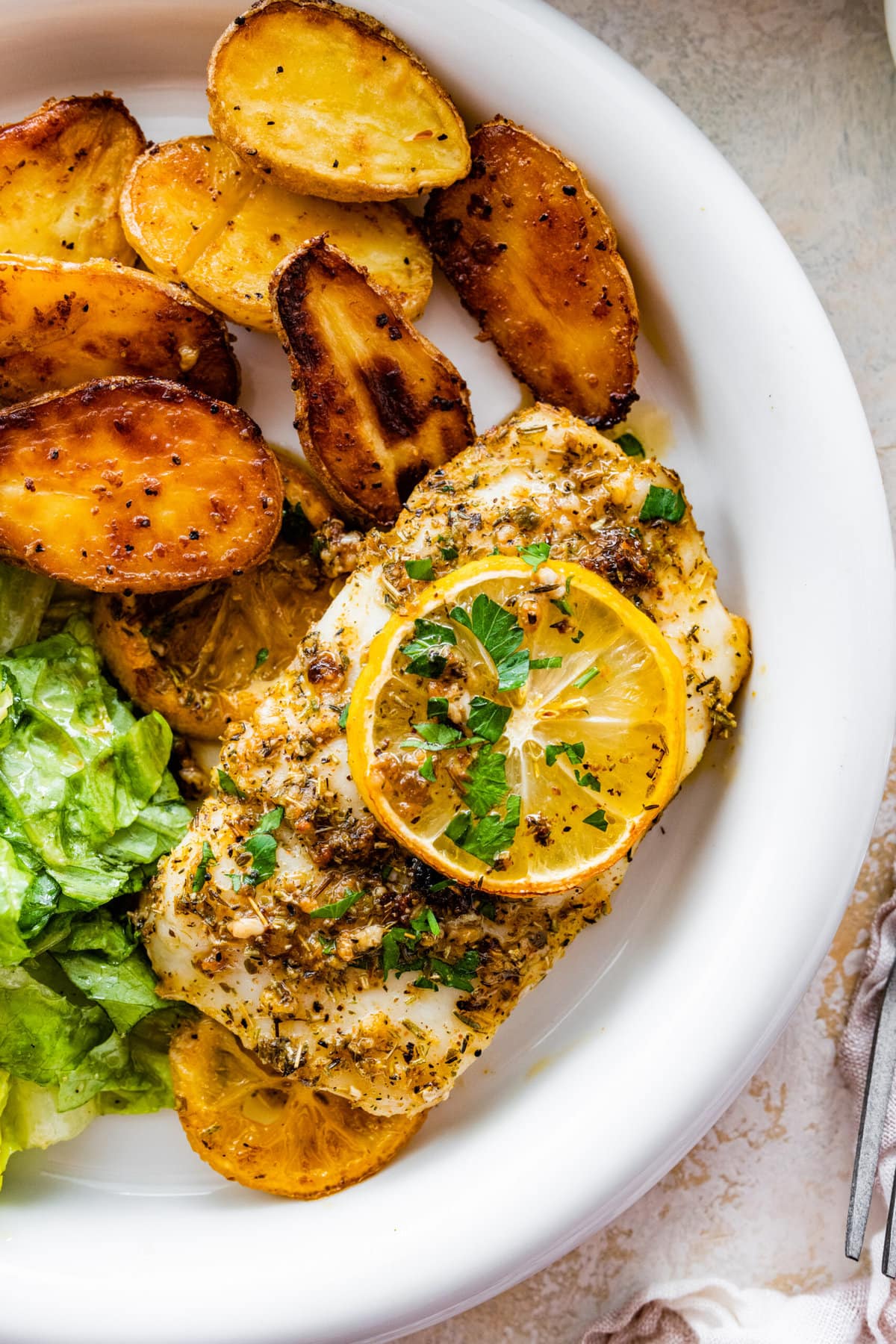 plated cod with oven baked potatoes and green salad.