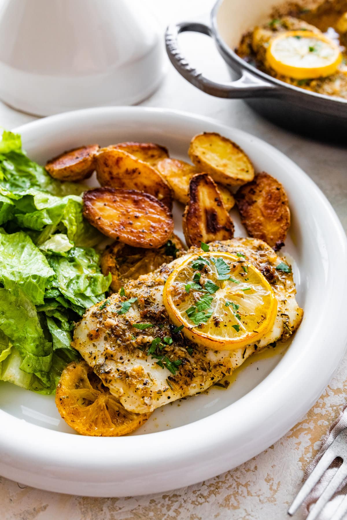 plated cod with oven baked potatoes and green salad.