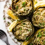 Stuffed artichokes and lemon wedges on a plate.