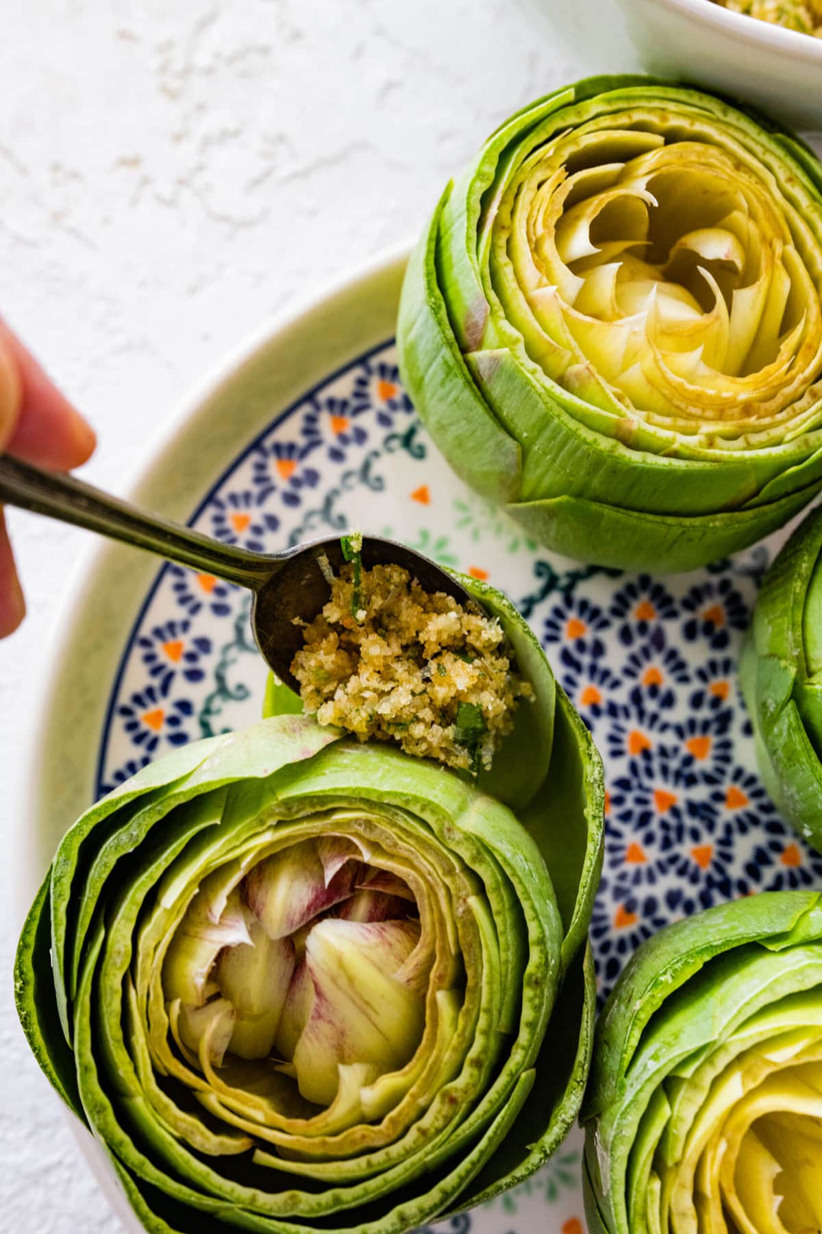 how to make stuffed artichokes step-by-step photos- filling the artichokes with the crumb filling.