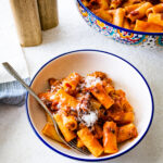 bowl of pasta alla zozzona recipe with the big serving Italian-style bowl of pasta in the background.