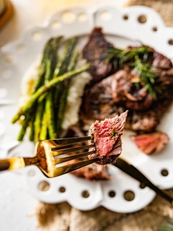 lamb steak on a plate with asparagus. Sliced meat on plate. Piece of meat on a fork ready to eat.