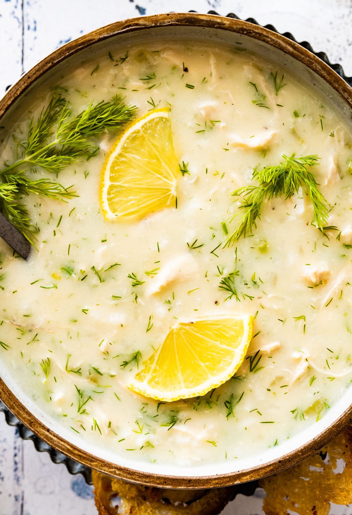 soup on a blue and white backdrop with fresh dill as garnish. Up close of soup. 