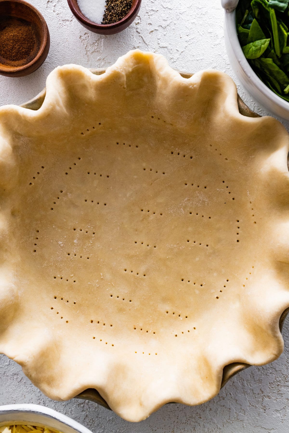 How to make spinach quiche step-by-step: Place pie crust in pie dish and poke with holes.