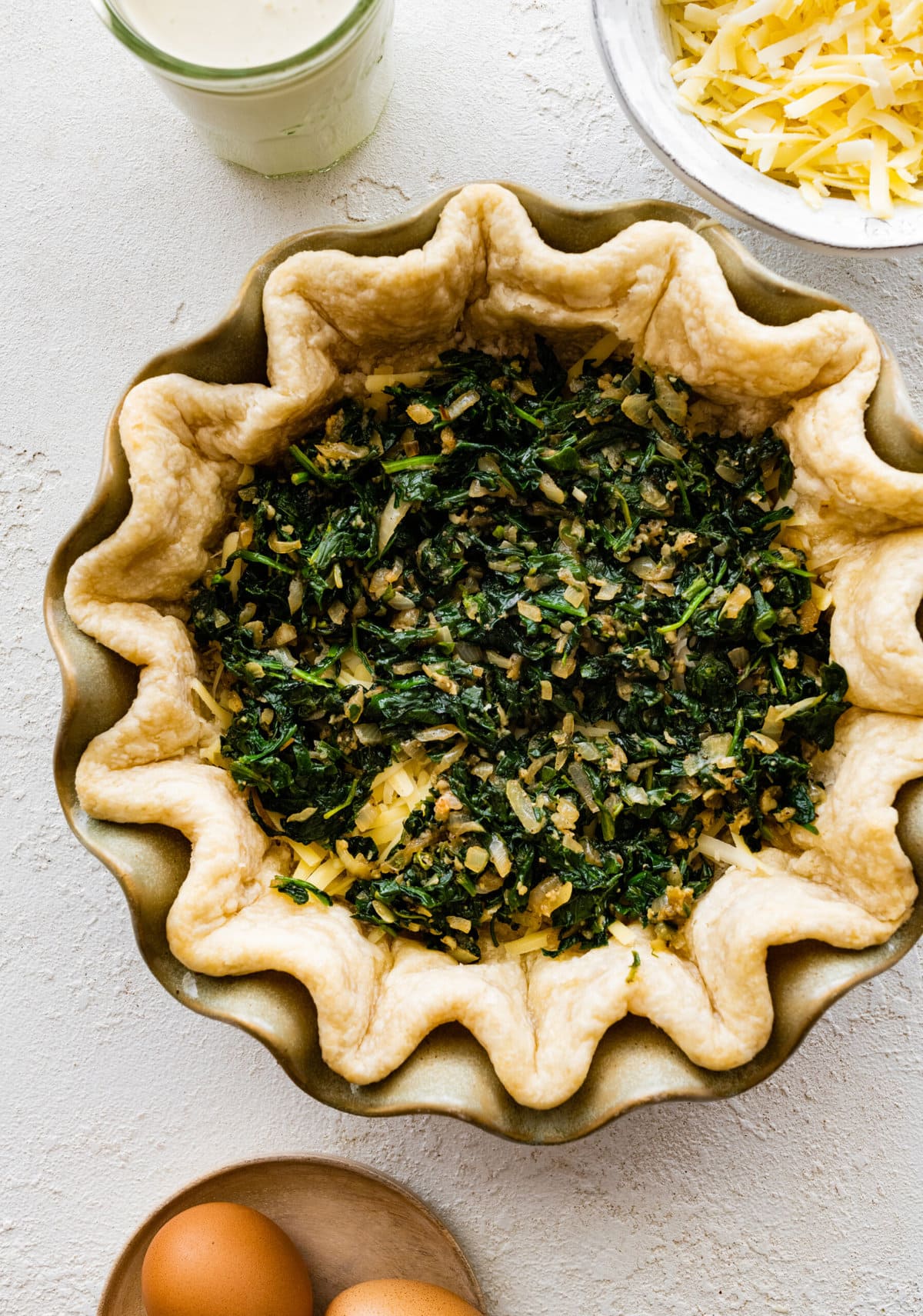 How to make spinach quiche step-by-step: add cooked spinach on top of the cheese.