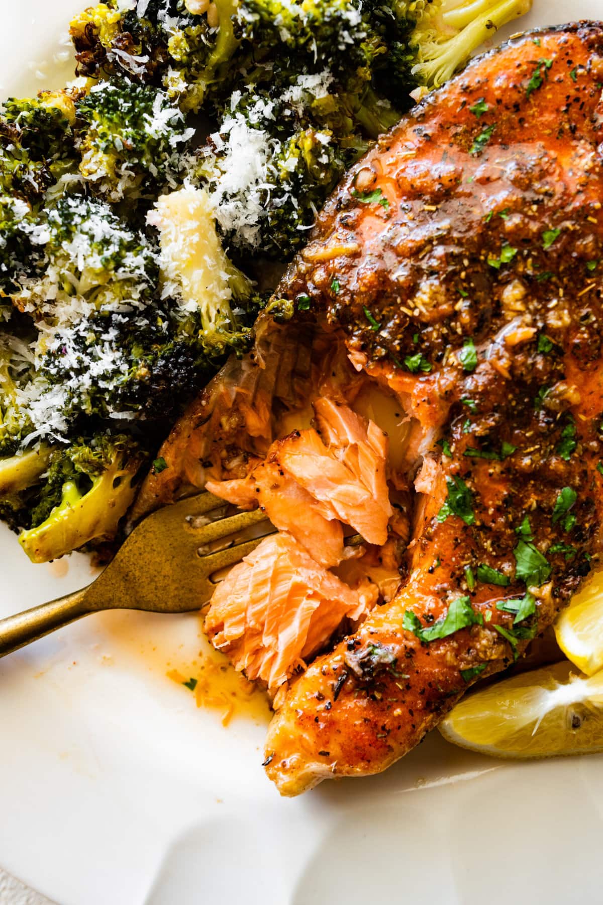 A plate with the easy oven baked salmon steaks recipe with roasted broccoli on the side. A bite taken out of the salmon.