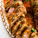 sliced pork tenderloin on a white serving platter.