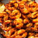 grilled longhorn steakhouse redrock shrimp on a platter ready to eat. Grilled lemon and butter dipping sauce on the side. Sunlight on the platter.