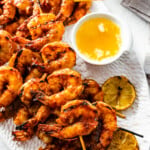 grilled longhorn steakhouse redrock shrimp on a platter ready to eat. Grilled lemon and butter dipping sauce on the side. Sunlight on the platter.