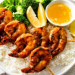 redrock shrimp on a plate with broccoli, rice, and butter dipping sauce.