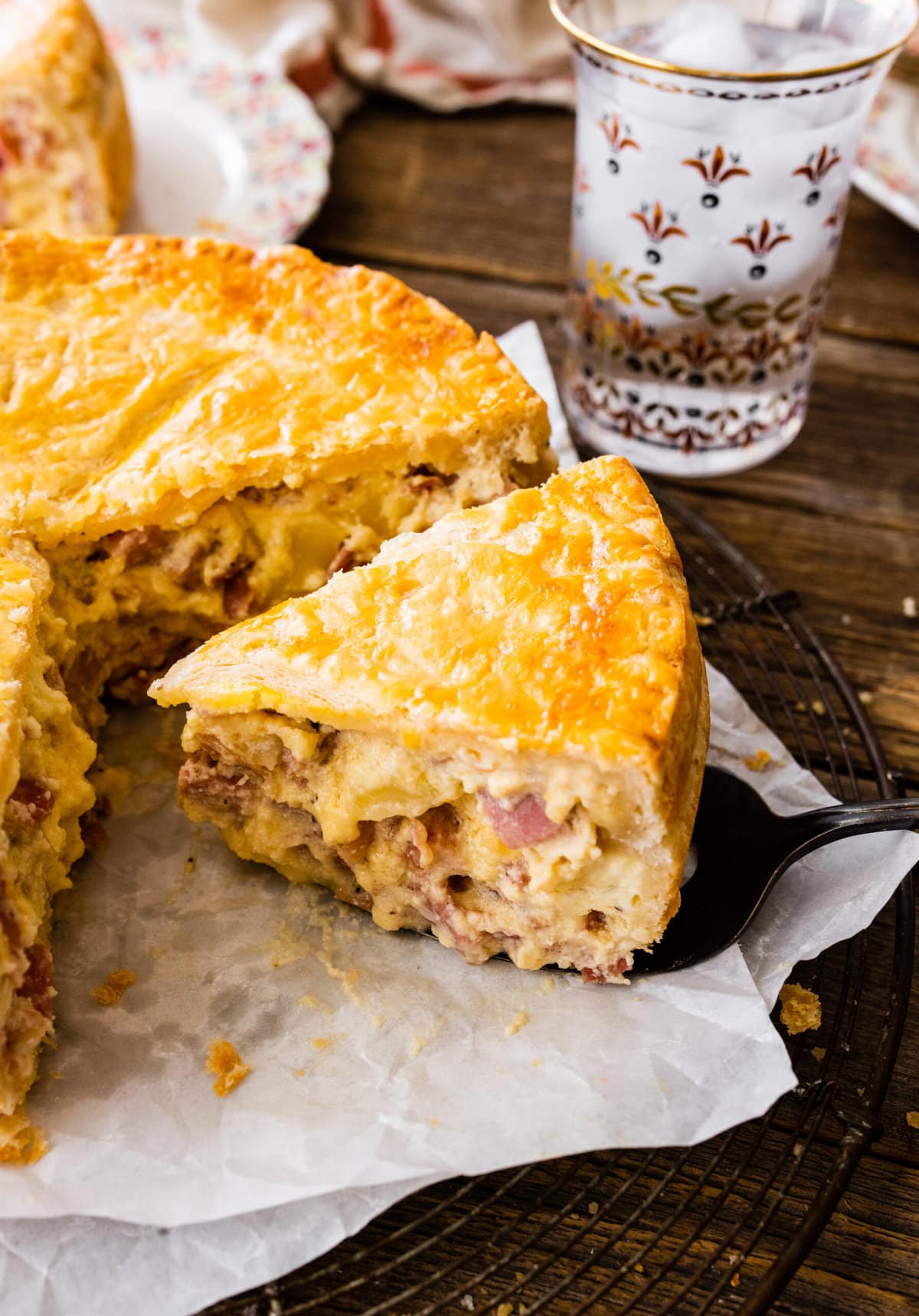 pizza rustica (Italian Easter pie) on a serving plate. Pie server taking out one slice. 