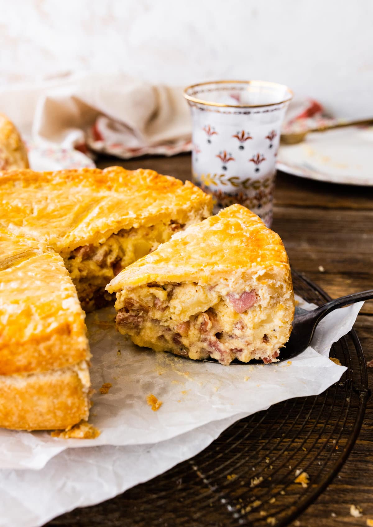 pizza rustica (Italian Easter pie) on a serving plate. Pie server taking out one slice.