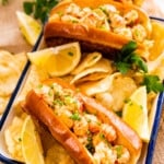 assembled sandwiches in a white and blue tray with chips and lemon wedges on the side.