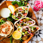 plate of falafel pitas with all the condiments in the pita. Plus a bowl of hummus and extra sauce. and pickled red onions.