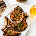 Juicy grilled pork chops on a plate with parsley on top.