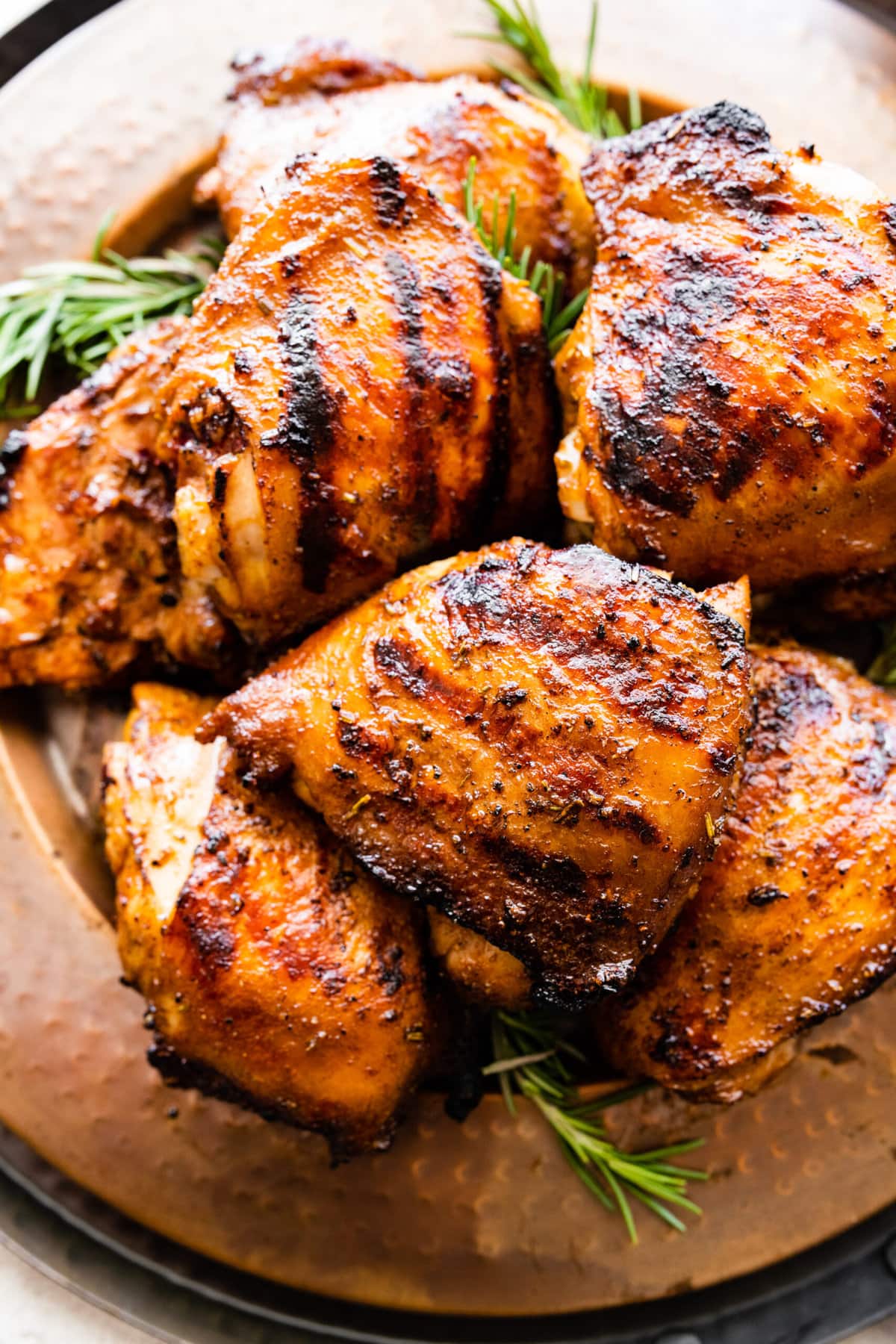 finished grilled chicken thighs on a serving platter with herbs on the side. Ready to serve and eat. 