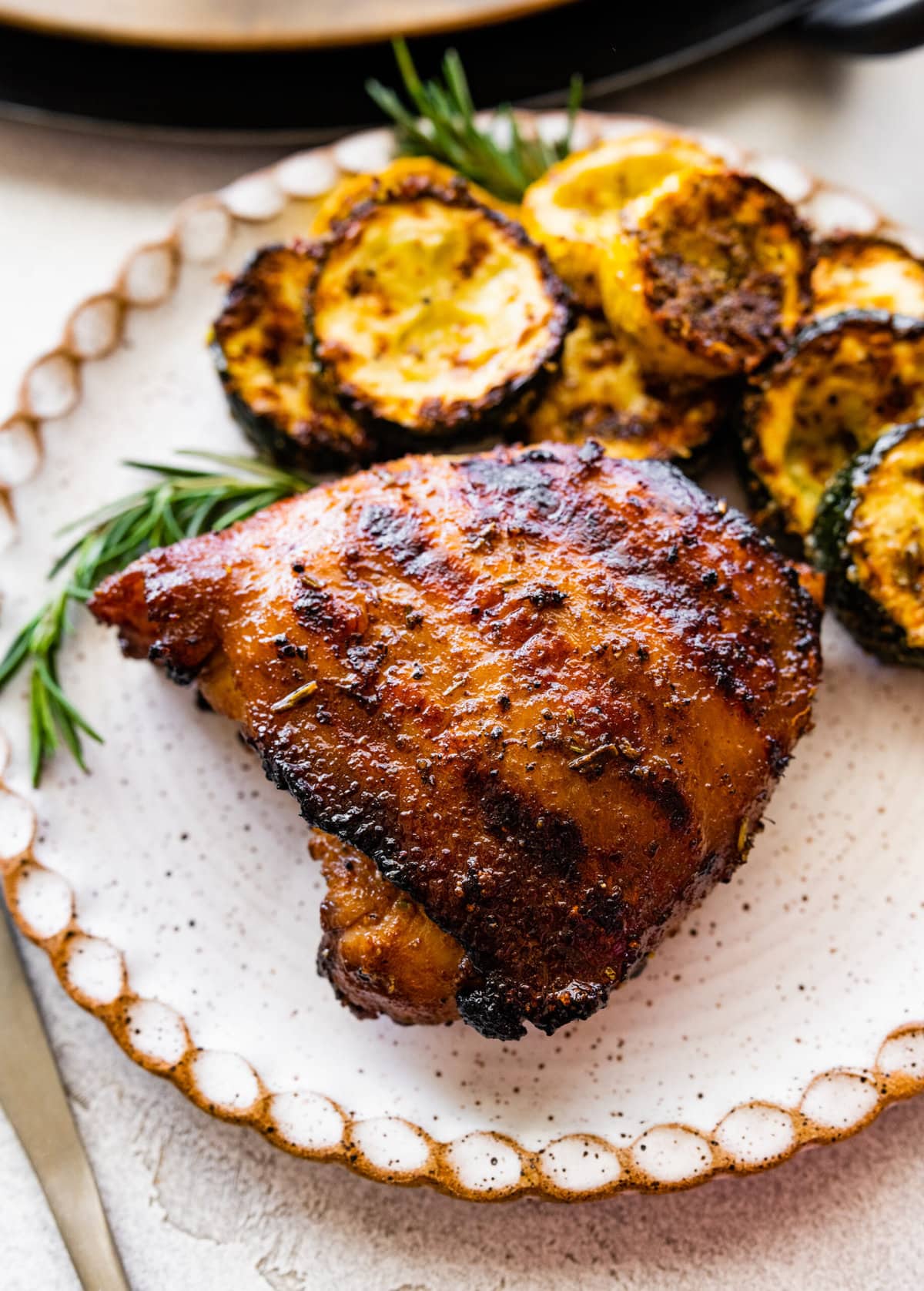 grilled chicken thighs in a plate with grilled lemon wedges.