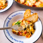 plate of the layered Eggplant, Zucchini, Tomato Casserole with a fork and bread on the side.