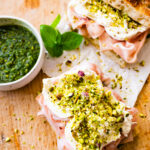 Assembled Mortadella Sandwich Recipe with Pistachio Pesto and Burrata with pesto on the side. Open faced to see the inside. Ready to eat.