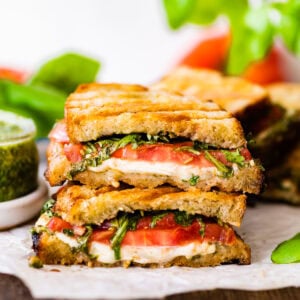 stacked basil pesto paninis with a jar of pesto.