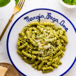 platted bowl of pasta with cheese. The bowl is white and in blue is written the Italian phrase- "Mangia, Prega, Ama".