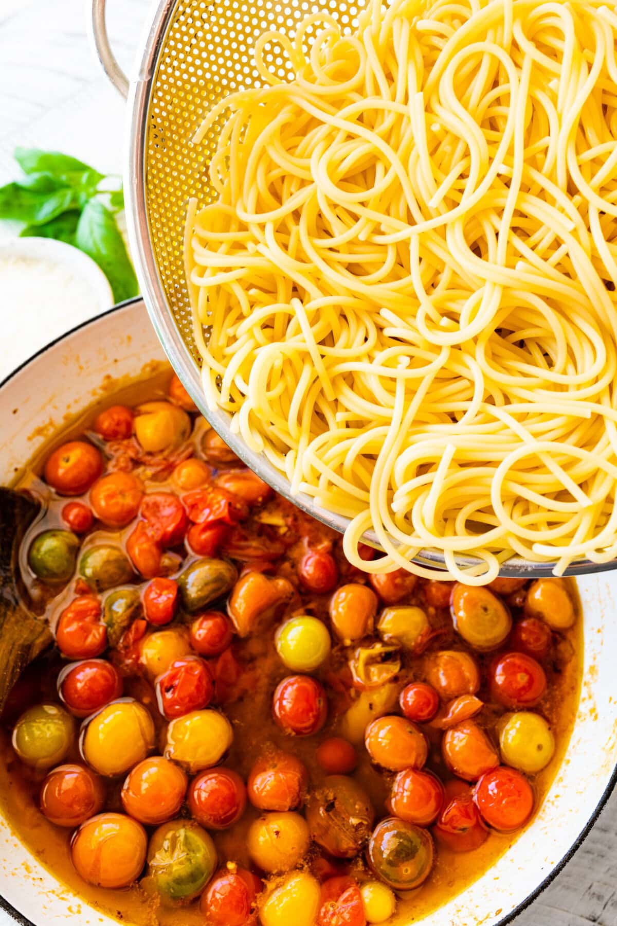 how to make easy burst cherry tomato pasta step-by-step instructions: adding the cooked pasta to the pan with cooked cherry tomatoes.