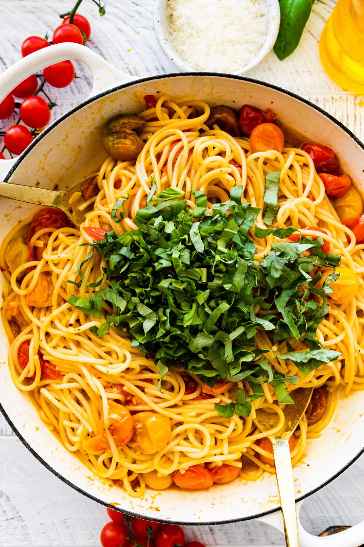 how to make easy burst cherry tomato pasta step-by-step instructions: adding the cooked pasta to the pan with cooked cherry tomatoes. Adding basil.