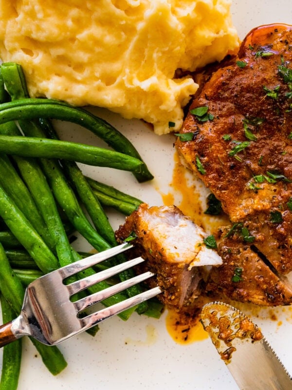 baked pork chops on a plate with green beans and mashed potatoes.