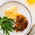 baked pork chops on a plate with green beans and mashed potatoes.