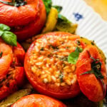 Best stuffed tomatoes on a beautiful blue and white platter with potatoes on the side.