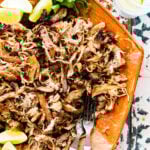 Chipotle Carnitas Copycat (slow cooker) on a platter with limes and cilantro.