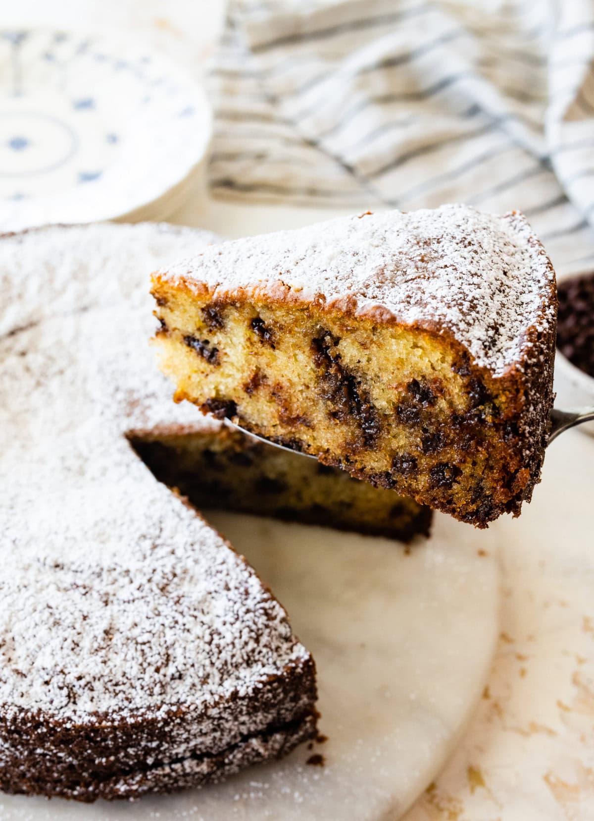 cake server holding a thick slice of the chocolate chip ricotta cake. The chocolate chips are visible.