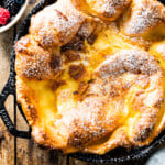 Dutch baby pancake topped with powdered sugar in a cast iron skillet.