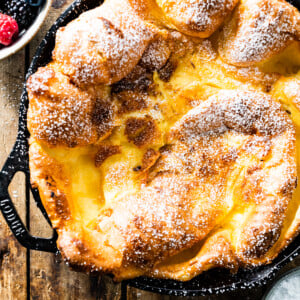Dutch baby pancake topped with powdered sugar in a cast iron skillet.